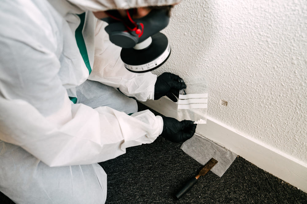 Technicien effectuant un prélèvement au sol pour analyse amiante dans le cadre du Dossier Technique Amiante (DTA)