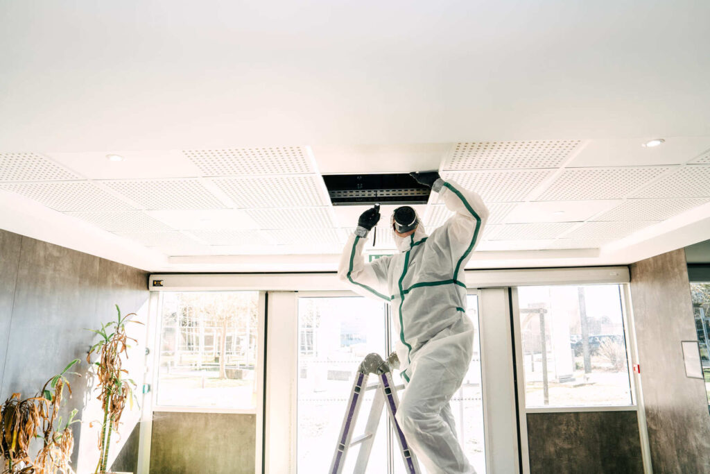 Technicien BTP Diagnostics réalisant un prélèvement d’échantillon sous un faux plafond dans le cadre d’un diagnostic amiante DTA.