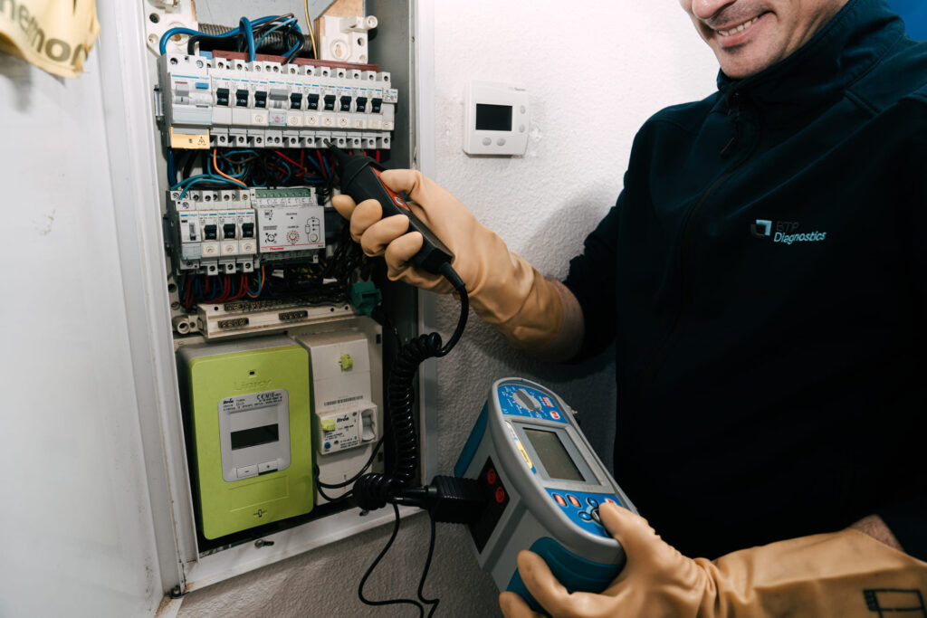 Diagnostiqueur BTP Diagnostics effectuant un contrôle électrique sur tableau de répartition.
