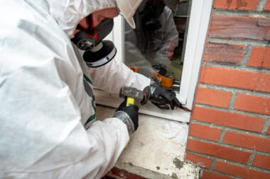 Technicien réalisant un repérage amiante avant travaux (RAAT) avec prélèvement sur un mur existant